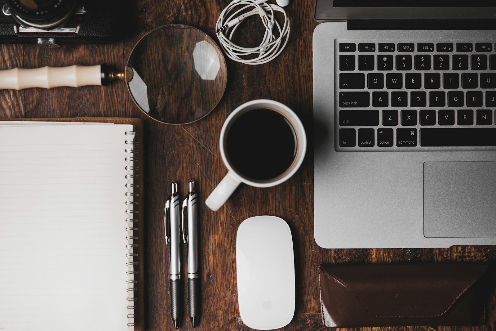 A notebook, pen and laptop laid out on a desk